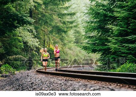 Young woman and teenage girl running along rural train track View Large Photo Image Stock Image - Young woman and teenage girl running along rural train track. Fotosearch