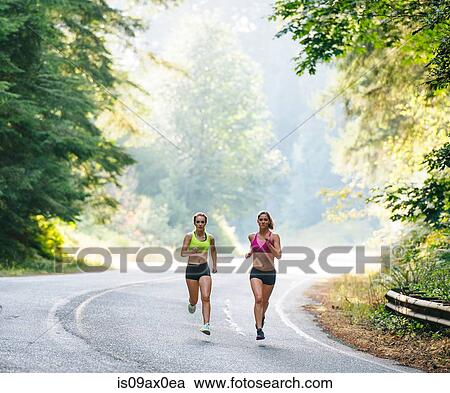 Young woman and teenage girl running along rural road View Large Photo Image Stock Image - Young woman and teenage girl running along rural road. Fotosearch