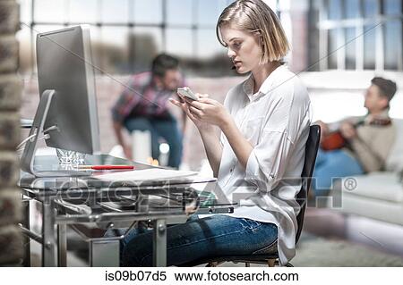 Young woman at home, working at desk, using smartphone View Large Photo Image Stock Photography - Young woman at home, working at desk, using smartphone. Fotosearch