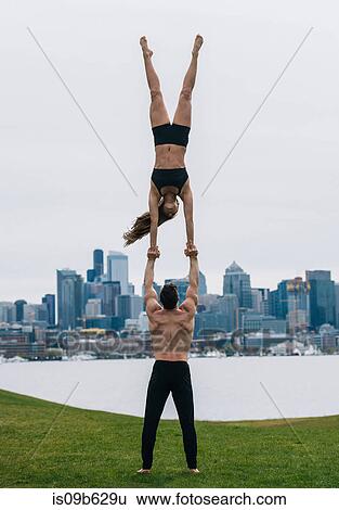 Young woman balancing on man's hands, full length, practicing yoga in front of Seattle skyline View Large Photo Image Stock Photograph - Young woman balancing on man's hands, full length, practicing yoga in front of Seattle skyline. Fotosearch