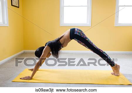 Young woman bending over in yoga pose on yoga mat View Large Photo Image Stock Photograph - Young woman bending over in yoga pose on yoga mat. Fotosearch