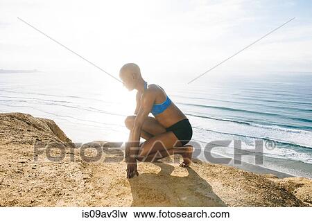 Young woman crouching on rocks beside sea View Large Photo Image Stock Photo - Young woman crouching on rocks beside sea. Fotosearch