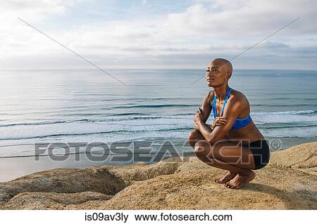 Young woman crouching on rocks beside sea View Large Photo Image Stock Photo - Young woman crouching on rocks beside sea. Fotosearch