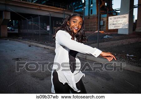 Young woman dancing in street, smiling View Large Photo Image Stock Image - Young woman dancing in street, smiling. Fotosearch