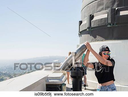 Stock Image - Young woman fooling around with coin binoculars at Griffith Observatory, Los Angeles, California, USA. Fotosearch