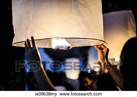 Young woman holding lit paper lantern waiting to release at Loy Krathong Paper Lantern Festival in Chiang Mai, Thailand View Large Photo Image Stock Photo - Young woman holding lit paper lantern waiting to release at Loy Krathong Paper Lantern Festival in Chiang Mai, Thailand. Fotosearch