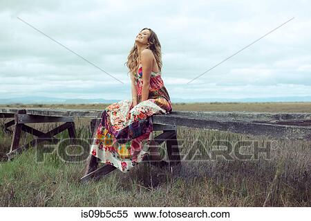 Young woman in boho maxi dress sitting on elevated wooden walkway in landscape View Large Photo Image Stock Photography - Young woman in boho maxi dress sitting on elevated wooden walkway in landscape. Fotosearch
