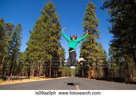Young woman jumping mid air on forest road, Sisters, Oregon, USA View Large Photo Image Stock Image - Young woman jumping mid air on forest road, Sisters, Oregon, USA. Fotosearch