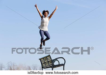 Young woman jumping off park bench View Large Photo Image Stock Photography - Young woman jumping off park bench. Fotosearch