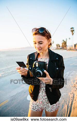 Young woman looking at instant photograph on beach, Venice Beach, California, USA View Large Photo Image Stock Photo - Young woman looking at instant photograph on beach, Venice Beach, California, USA. Fotosearch