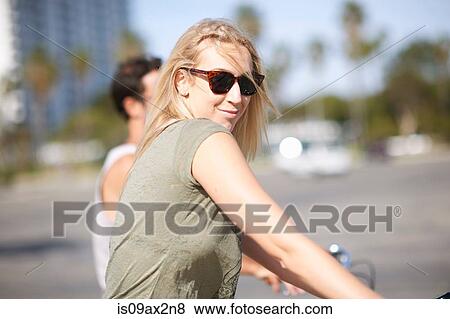 Young woman looking over her shoulder whilst cycling with boyfriend at Venice Beach, Los Angeles, California, USA View Large Photo Image Stock Photo - Young woman looking over her shoulder whilst cycling with boyfriend at Venice Beach, Los Angeles, California, USA. Fotosearch