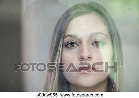 Stock Photography - Young woman looking through glass, close-up. Fotosearch
