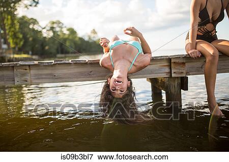 Stock Photo - Young woman lying back on pier dangling long wet hair, Santa Rosa Beach, Florida, USA. Fotosearch
