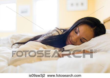 Young woman lying in bed asleep View Large Photo Image Stock Image - Young woman lying in bed asleep. Fotosearch