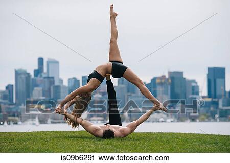Young woman lying on back balancing on man's hands, practicing yoga in front of Seattle skyline View Large Photo Image Stock Photograph - Young woman lying on back balancing on man's hands, practicing yoga in front of Seattle skyline. Fotosearch