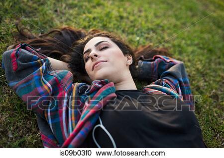 Young woman lying on grass, eyes closed View Large Photo Image Stock Image - Young woman lying on grass, eyes closed. Fotosearch