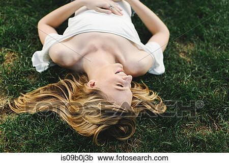 Young woman lying on grass, laughing View Large Photo Image Stock Image - Young woman lying on grass, laughing. Fotosearch
