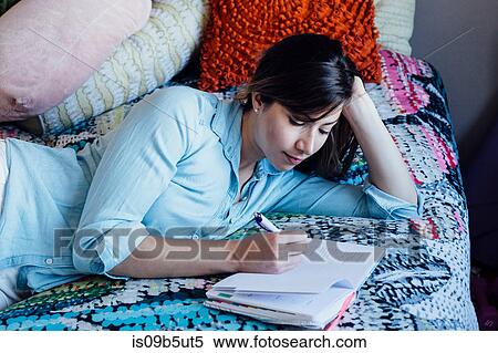 Young woman lying on shabby chic bed writing in notebook View Large Photo Image Stock Photography - Young woman lying on shabby chic bed writing in notebook. Fotosearch