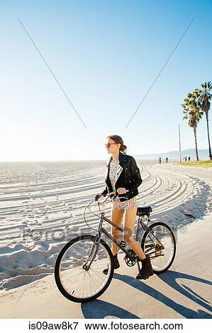 Young woman on bicycle gazing from beach, Venice Beach, California, USA View Large Photo Image Stock Photo - Young woman on bicycle gazing from beach, Venice Beach, California, USA. Fotosearch