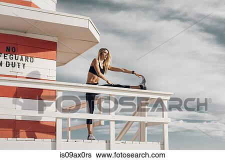 Stock Photograph - Young woman on lifeguard platform, exercising. Fotosearch