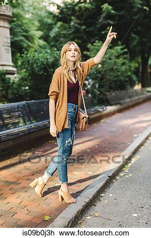 Young woman outdoors, hailing taxi View Large Photo Image Stock Image - Young woman outdoors, hailing taxi. Fotosearch