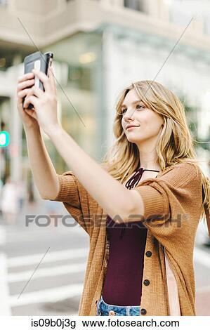 Young woman outdoors, taking selfie with smartphone View Large Photo Image Stock Image - Young woman outdoors, taking selfie with smartphone. Fotosearch