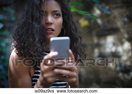 Young woman outdoors, using smartphone View Large Photo Image Stock Photo - Young woman outdoors, using smartphone. Fotosearch