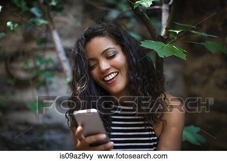 Stock Photo - Young woman outdoors, using smartphone. Fotosearch