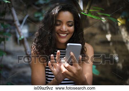 Stock Photo - Young woman outdoors, using smartphone. Fotosearch