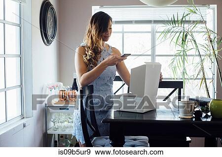 Young woman photographing opened cake box on table View Large Photo Image Stock Photo - Young woman photographing opened cake box on table. Fotosearch