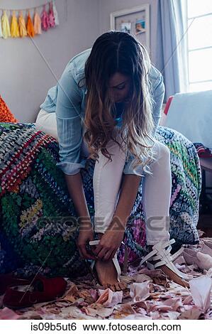 Young woman putting sandals on in bedroom View Large Photo Image Stock Photograph - Young woman putting sandals on in bedroom. Fotosearch