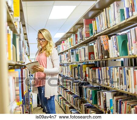 Stock Photo - Young woman reading book from library shelves. Fotosearch