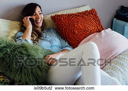 Young woman reclining on shabby chic bed making smartphone call View Large Photo Image Stock Image - Young woman reclining on shabby chic bed making smartphone call. Fotosearch