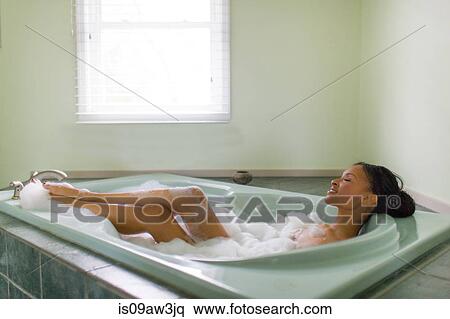 Stock Photography - Young woman relaxing in bubble bath with feet up. Fotosearch