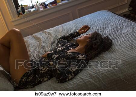 Young woman relaxing on bed, looking out of window View Large Photo Image Stock Photo - Young woman relaxing on bed, looking out of window. Fotosearch