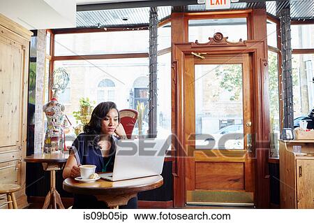 Young woman sitting in cafe, using laptop View Large Photo Image Stock Photography - Young woman sitting in cafe, using laptop. Fotosearch