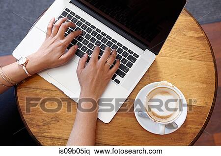 Young woman sitting in cafe, using laptop, overhead view View Large Photo Image Stock Photography - Young woman sitting in cafe, using laptop, overhead view. Fotosearch
