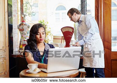 Young woman sitting in cafe, using laptop View Large Photo Image Stock Photography - Young woman sitting in cafe, using laptop. Fotosearch