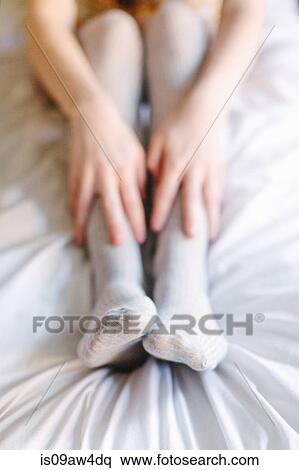 Young woman sitting on bed, hands on legs, close-up View Large Photo Image Stock Photography - Young woman sitting on bed, hands on legs, close-up. Fotosearch