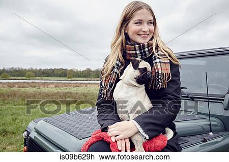 Young woman sitting on off road vehicle in field with dog on lap View Large Photo Image Stock Image - Young woman sitting on off road vehicle in field with dog on lap. Fotosearch