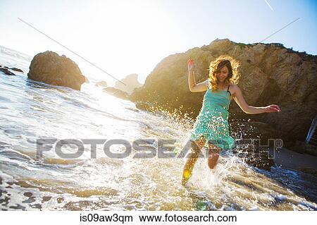 Young woman splashing in water on beach View Large Photo Image Picture - Young woman splashing in water on beach. Fotosearch