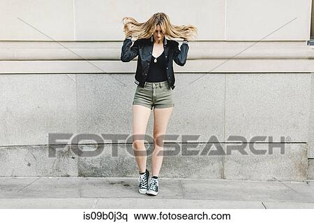 Young woman standing in street, tousling hair View Large Photo Image Stock Photography - Young woman standing in street, tousling hair. Fotosearch