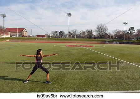 Young woman standing on sports field in yoga position View Large Photo Image Stock Photography - Young woman standing on sports field in yoga position. Fotosearch