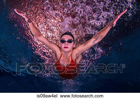 Stock Image - Young woman swimming underwater. Fotosearch