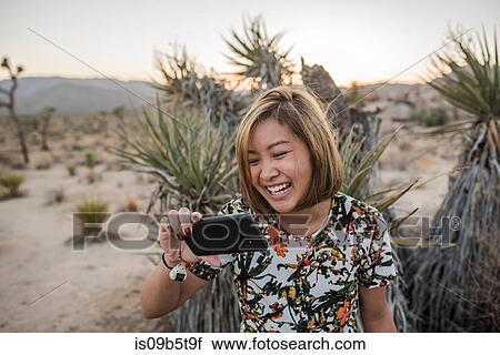 Stock Image - Young woman taking smartphone selfie in Joshua Tree National Park at dusk, California, USA. Fotosearch