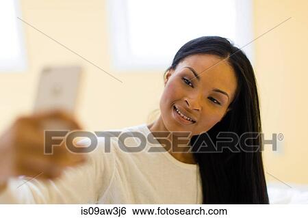 Young woman taking smartphone selfie View Large Photo Image Stock Photograph - Young woman taking smartphone selfie. Fotosearch
