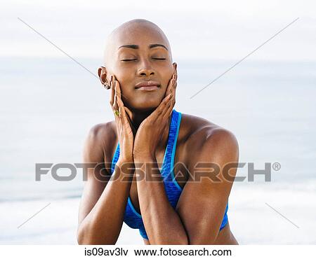 Stock Photo - Young woman, touching face, eyes closed, smiling, outdoors. Fotosearch