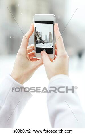 Stock Image - Young woman using smartphone to photograph the Christian Science Centre and Prudential building with snow, Boston, Massachusetts, USA. Fotosearch