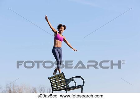 Young woman walking along edge of bench View Large Photo Image Picture - Young woman walking along edge of bench. Fotosearch