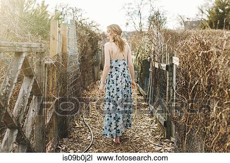 Young woman walking along rural farm pathway, rear view View Large Photo Image Stock Image - Young woman walking along rural farm pathway, rear view. Fotosearch